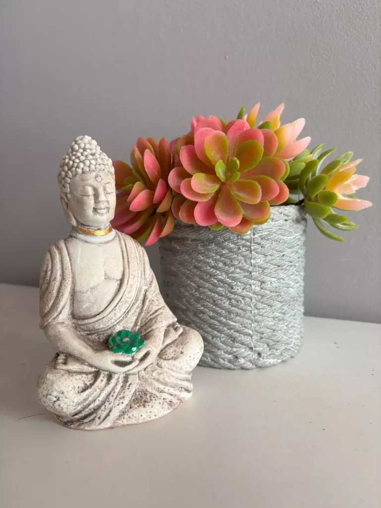 Figura de un buda junto a un jarrón con flores
